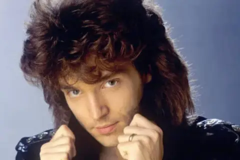 Richard Marx z burzą włosów i w skórzanej kurtce, jakby śpiewał "Right Here Waiting".