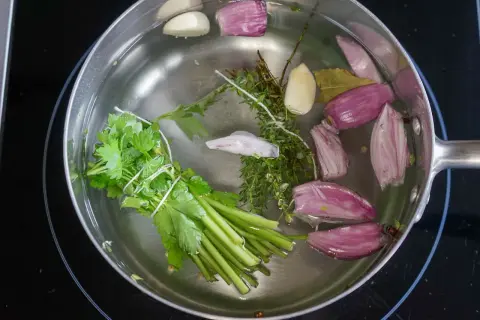 Préparation d'un court-bouillon avec oignons, ail, thym, persil et laurier. Idéal pour le temps de cuisson seiche au court-bouillon.