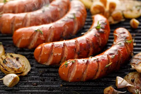 Soczysta kiełbasa śląska z grilla, parująca i pachnąca. Obok grillowana cebula i czosnek. Idealna na letnie wieczory, choć warto sprawdzić kiełbasa śląska kcal.