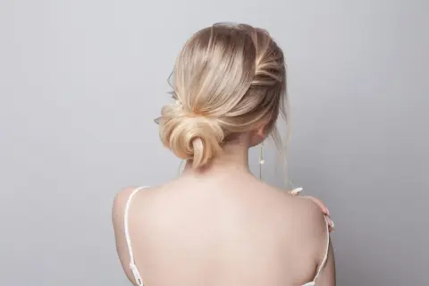 Elegancki kok z blond włosów, spięte spinką z perłą, podkreśla delikatność stylizacji.