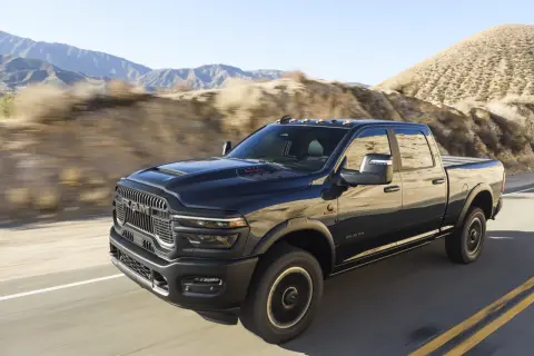 Czarny Dodge Ram 2500 pędzi po pustynnej drodze, góry w tle.