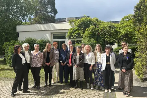 Un groupe de personnes, dont un officier d'académie, pose devant un bâtiment.