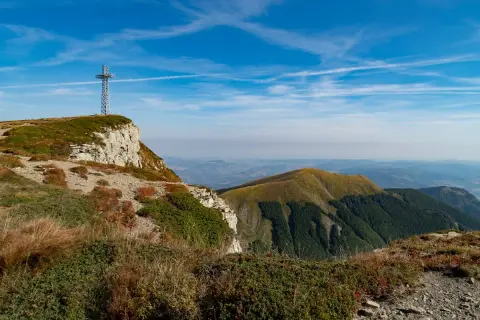 Croce metallica su un crinale roccioso, con vista panoramica sulle colline verdi dell'Emilia Romagna. Perfetto per escursioni.