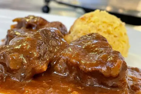Un saporito gulash trentino, con carne tenera in salsa ricca e una porzione di polenta dorata.