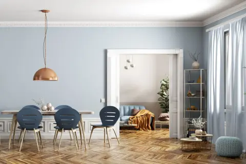 Helle Räume mit wandgestaltung streifen waagerecht in sanftem Blau. Ein Esstisch mit blauen Stühlen und eine gemütliche Sitzecke im Hintergrund.