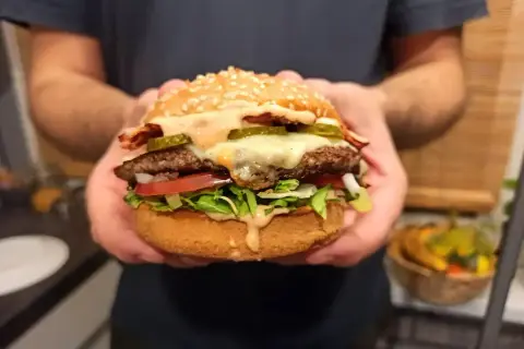 Idealny burger: soczysta wołowina, ser, chrupiąca sałata, pomidor, ogórek i sos. Oto jak składać burgera krok po kroku.