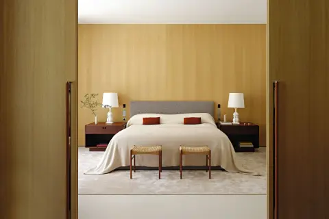 Modernes Schlafzimmer mit Holzakzenten, einem bequemen Bett und zwei Hockern. Tolle schlafzimmer ideen modern für ein stilvolles Zuhause.