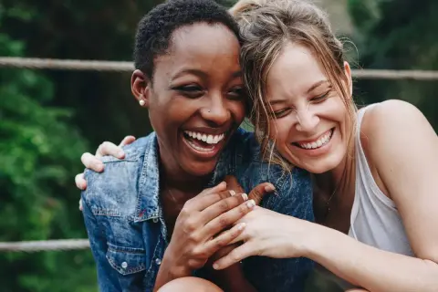Zwei lachende Frauen, die sich umarmen. Ein Bild, das die psychologische Definition von Freundschaft perfekt einfängt: Vertrauen, Nähe und Freude.