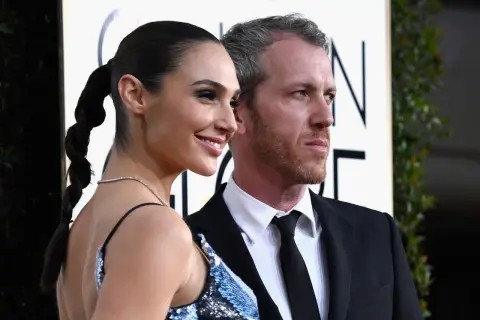 Yaron Varsano y su esposa, Gal Gadot, posan sonrientes en la alfombra dorada.