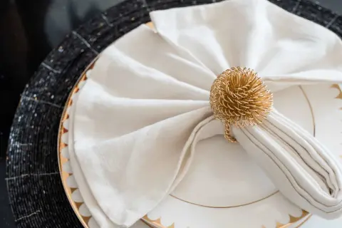 Vackert vika servetter med en gyllene ring som dekoration, redo för en festlig middag.