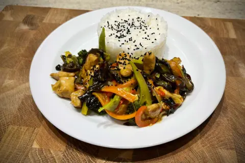 Pyszny kurczak w pięciu smakach z ryżem i warzywami, posypany czarnym sezamem.