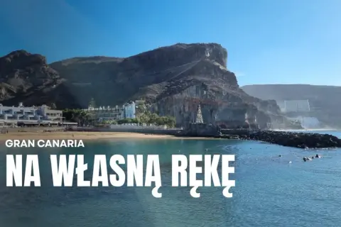 Gran Canaria zwiedzanie: malownicza plaża z hotelami i klifami w tle, błękitne morze.