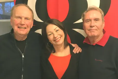 Sten Nilsson med familj, glada leenden och en röd bakgrund.