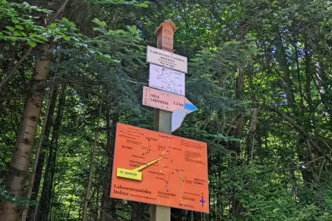 Tablica z drogowskazami w lesie. Wskazuje drogę do Hali Łabowskiej (2,3 km) i Doliny Łabowszczańskiej. Mapa szlaków turystycznych.