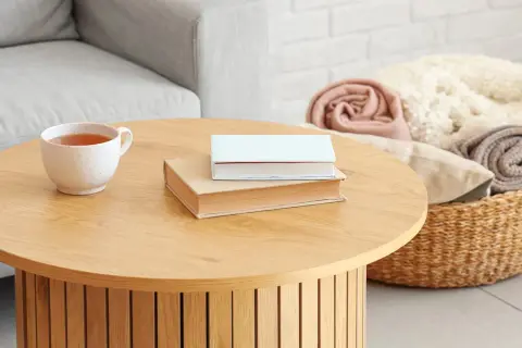 Kubek z herbatą i dwie książki na drewnianym stoliku. Idealne inspiracje, co postawić na stolik kawowy, by stworzyć przytulną atmosferę.