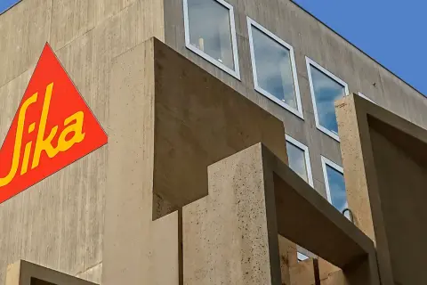 Edificio moderno de hormigón con el logo de Sika en rojo y amarillo.