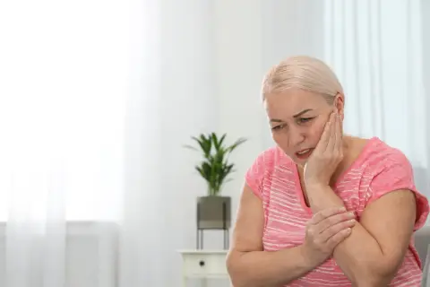 Donna con mano sulla guancia, espressione sofferente, forse per una bocca urente.