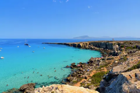 La spiaggia più bella di Favignana: acque cristalline, scogliere dorate e barche all'ancora. Un paradiso terrestre.