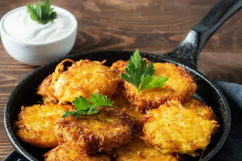Goldbraune Kartoffelpuffer im Gusseisenpfännchen, perfekt für ein Kartoffelpuffer Rezept. Dazu ein Schälchen cremiger Dip.