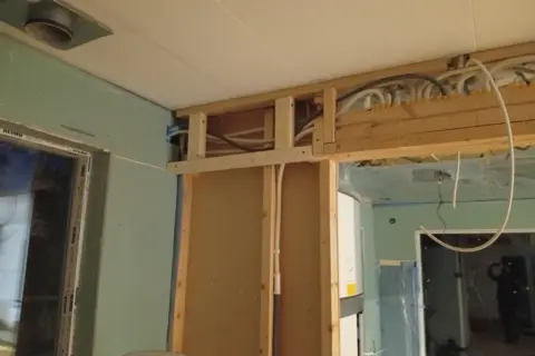 Pågående renovering av badrum med synliga rör och trästomme.