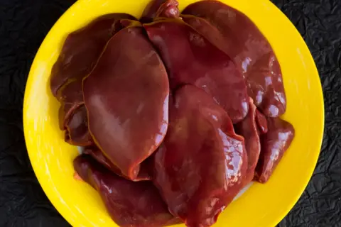 Surowa wątróbka na żółtym talerzu. Czy wątróbka jest tłusta? Wygląda na soczystą i gotową do smażenia.