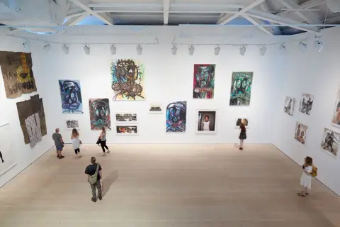 Visitors explore a vibrant exhibition, showcasing bold portraits and mixed media pieces that define the dynamic London art scene.