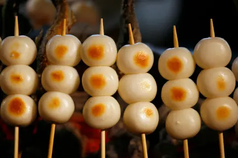 Proste japońskie dania: słodkie kluseczki mochi na patyczkach, lekko przypieczone.