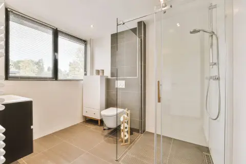 Salle de bain moderne avec douche italienne surélevée avec marche, toilettes suspendues et meuble vasque.