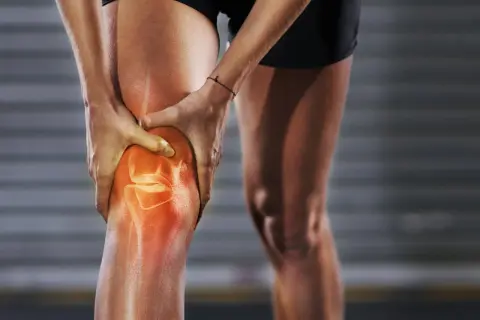 Sportlerin hält schmerzendes Knie. Rote Hitze zeigt Entzündung im Bereich der Kniekehle, die beim Laufen Probleme macht.