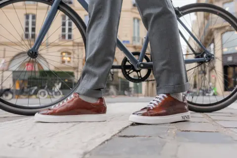 Eleganckie, brązowe sneakersy do garnituru, idealne na miejską przejażdżkę rowerem.