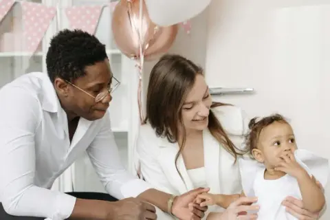 Famille célébrant la tradition du baptême. Un père, une mère et leur bébé, entourés de décorations festives.