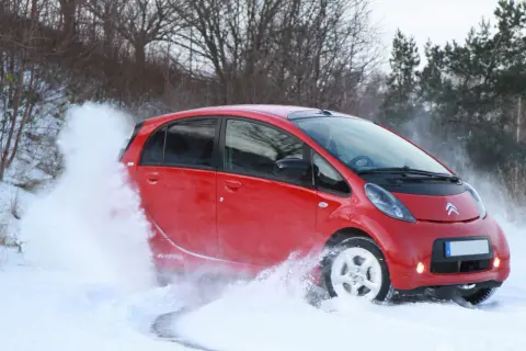 Röd Citroën C-Zero kör genom snö, skapar en stor snövirvel.