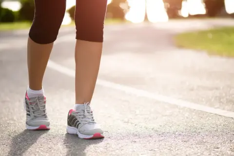 Kobieta w sportowych butach biegnie po asfaltowej ścieżce. Czy bieganie odchudza? Tak, regularny wysiłek pomaga spalić kalorie i osiągnąć wymarzoną sylwetkę.