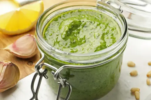 Domowe pesto w słoiku, obok czosnek i cytryna. Czy pesto ze słoika się podgrzewa? Zwykle nie, ale to zależy od przepisu.
