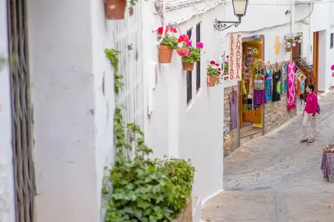 Calle estrecha en el centro de Almería, con casas blancas, flores y una tienda de ropa.