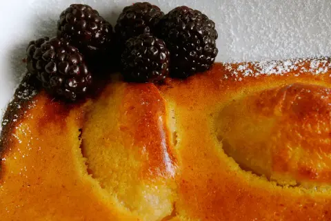 Delicioso postre de peras al horno, cubierto con moras frescas y espolvoreado con azúcar glas.