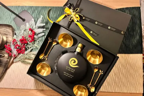 Elegante confezione regalo con olio d'oliva extra vergine, coppette e cucchiaini dorati. Regalare olio d'oliva ha un significato di benessere e cura.