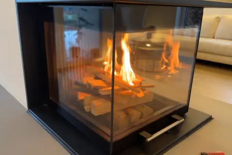 Ein moderner Kamin mit brennendem Holz. Die Flammen tanzen und geben ein warmes Licht ab, das die Frage aufwirft, wie lange brennt ein holzscheit wohl?