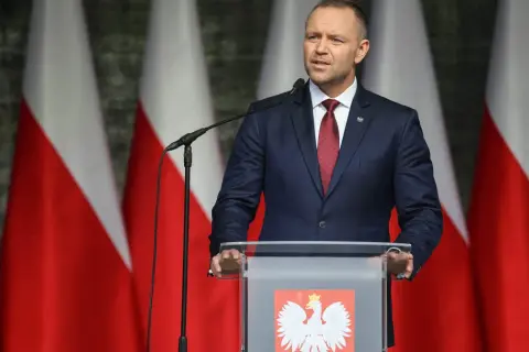 Mężczyzna w garniturze przemawia na tle flag Polski. Może właśnie użył swojego prawa weta.