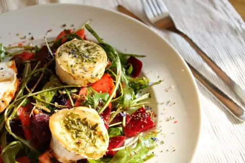 Ein köstlicher Rote Bete Salat mit Ziegenkäse, garniert mit Kräutern und Blüten.