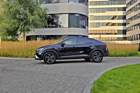 Elegancki, czarny Renault Arkana na tle nowoczesnych budynków. Sprawdź jego wymiary i styl.