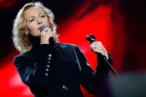 Artystka śpiewa z pasją, jakby mówiła "kocham cię życie tekst". Czerwone tło podkreśla jej emocje.