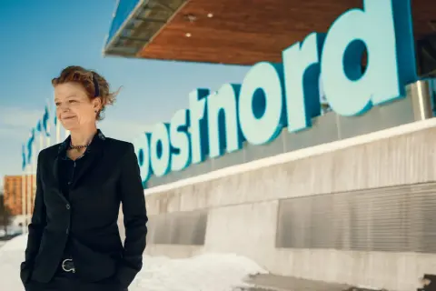 Annemarie Gardshol står framför Postnords logotyp en solig vinterdag.