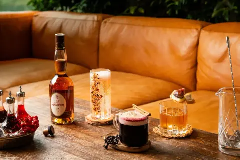 En flaska Calvados, en whisky sour med is och garnityr, en mörk drink med kanel och bär samt en bubblig dryck.