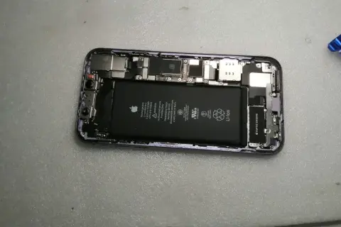Wnętrze iPhone'a z widoczną baterią i elementami płyty głównej.
