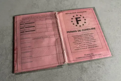 Un ancien permis de conduire français, rose, ouvert, montrant les catégories de véhicules et les mentions.
