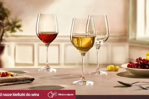 Eleganckie kieliszki do wina, jeden z czerwonym winem, drugi z białym, gotowe na degustacje. Obok winogrona i sztućce.