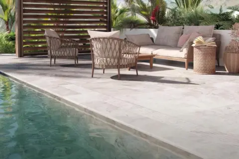 Terraza junto a piscina con mobiliario de exterior. El suelo antideslizante es el mejor suelo para exterior, seguro y elegante.