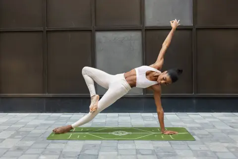 A woman in yoga attire performs a challenging pose on a mat, demonstrating how to block a hook with core strength and balance.