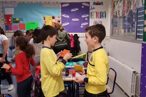 Niños participando en dinámicas de grupo en un aula, interactuando y compartiendo materiales.